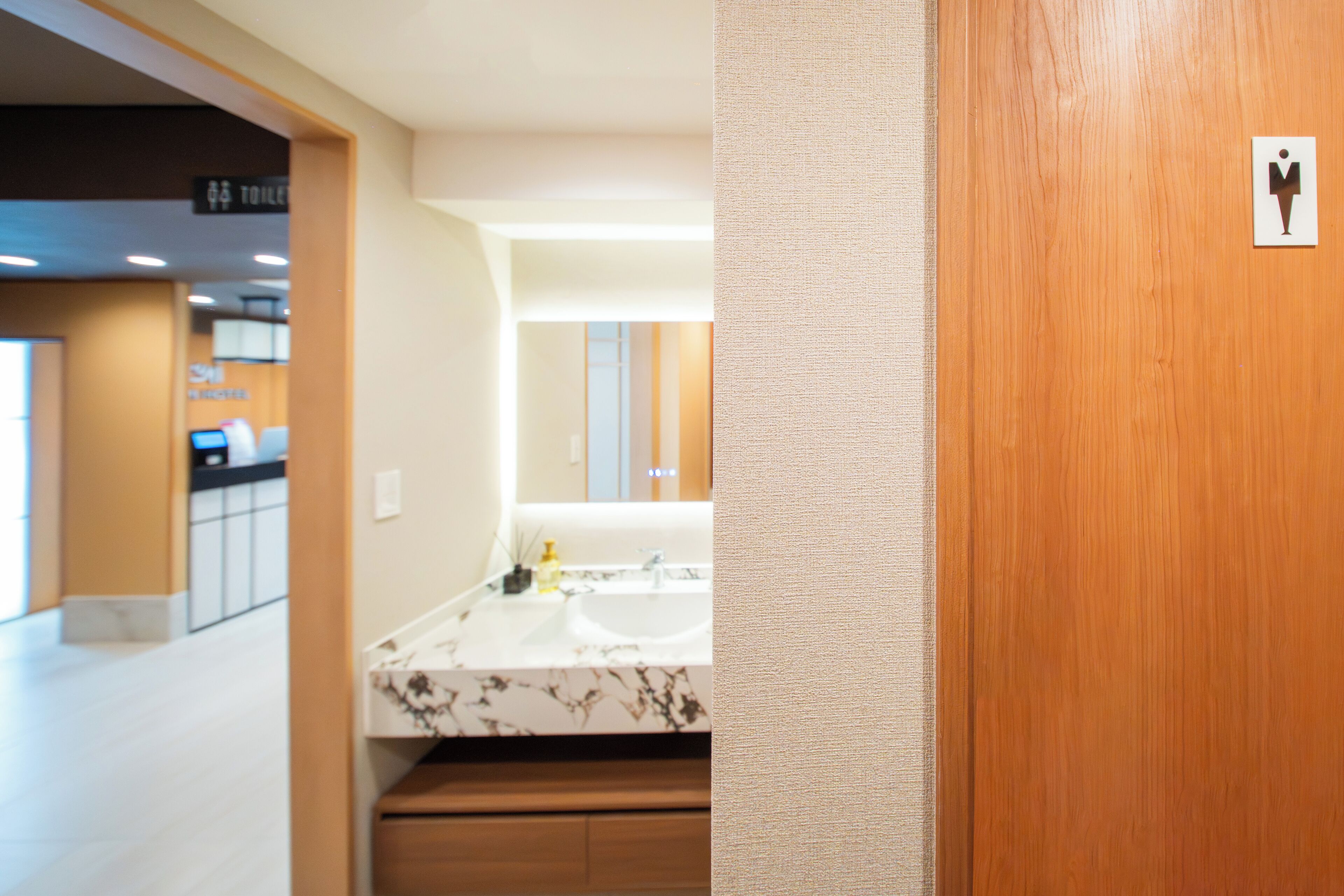 A modern bathroom with a marble sink, wooden cabinets, and a mirror.