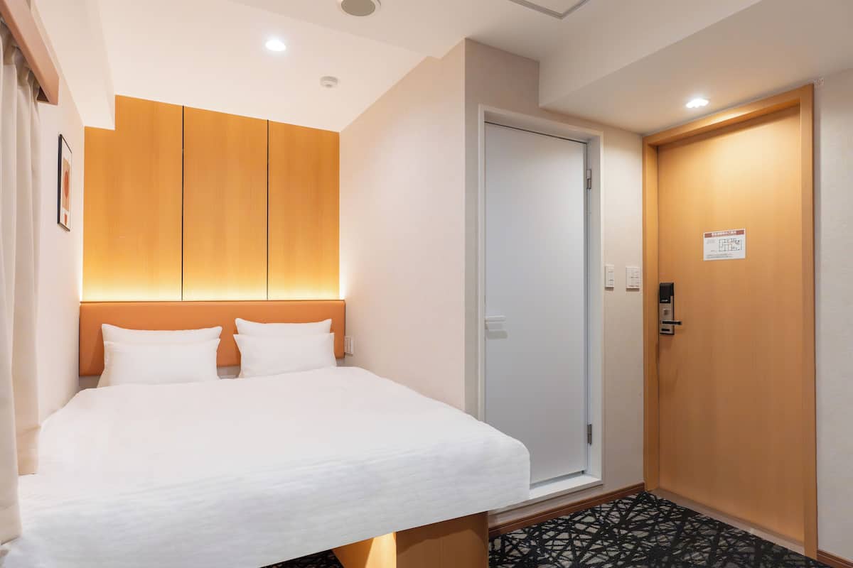 Una camera d'albergo con un letto, una testiera in legno, una porta e un pavimento decorato.