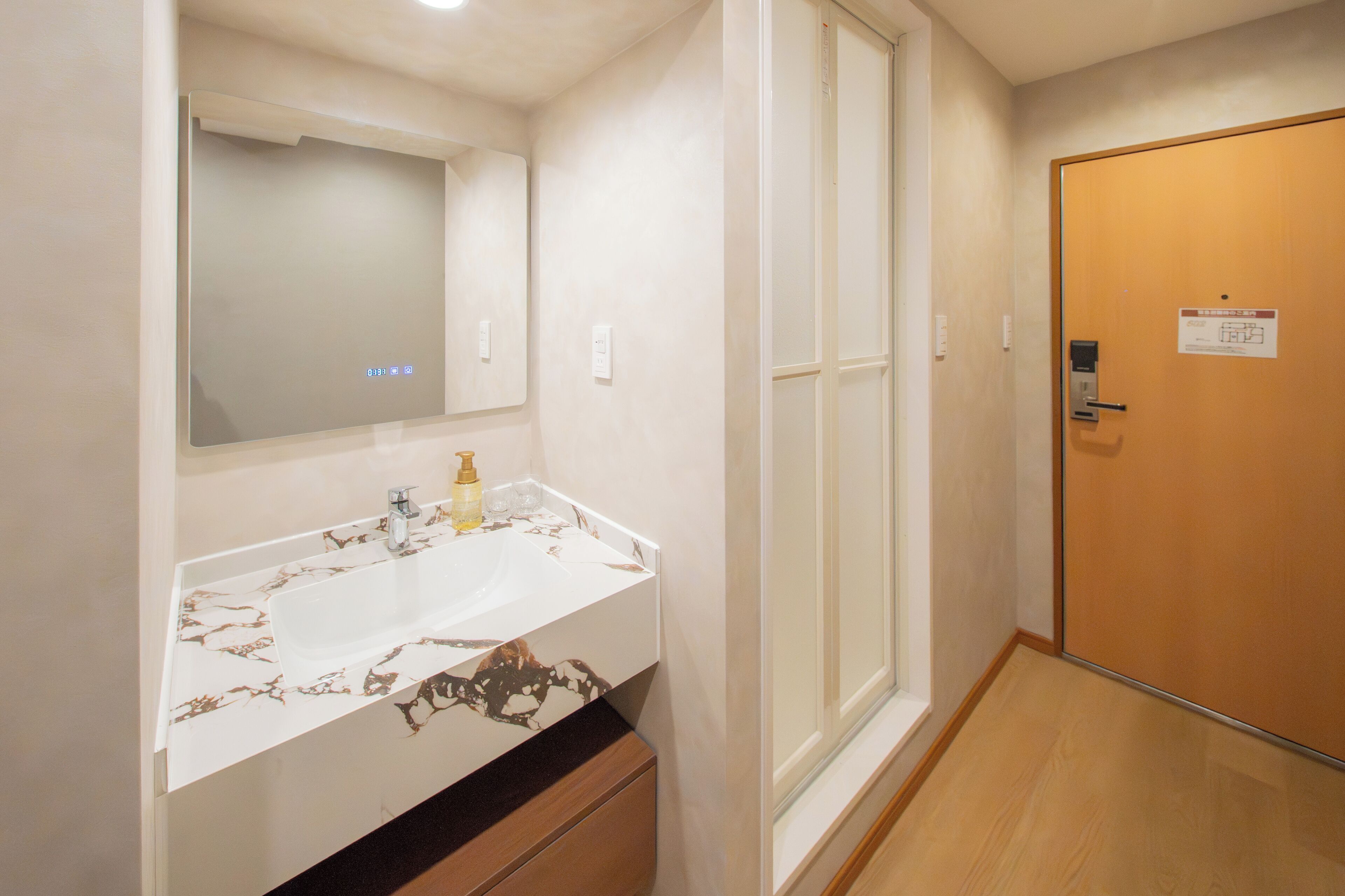 A bathroom with a marble sink, a mirror, and a wooden door.