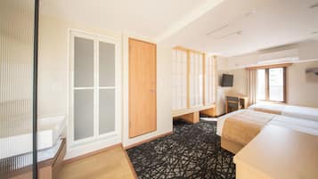 A hotel room with a wardrobe, a desk, a bed, and a television.