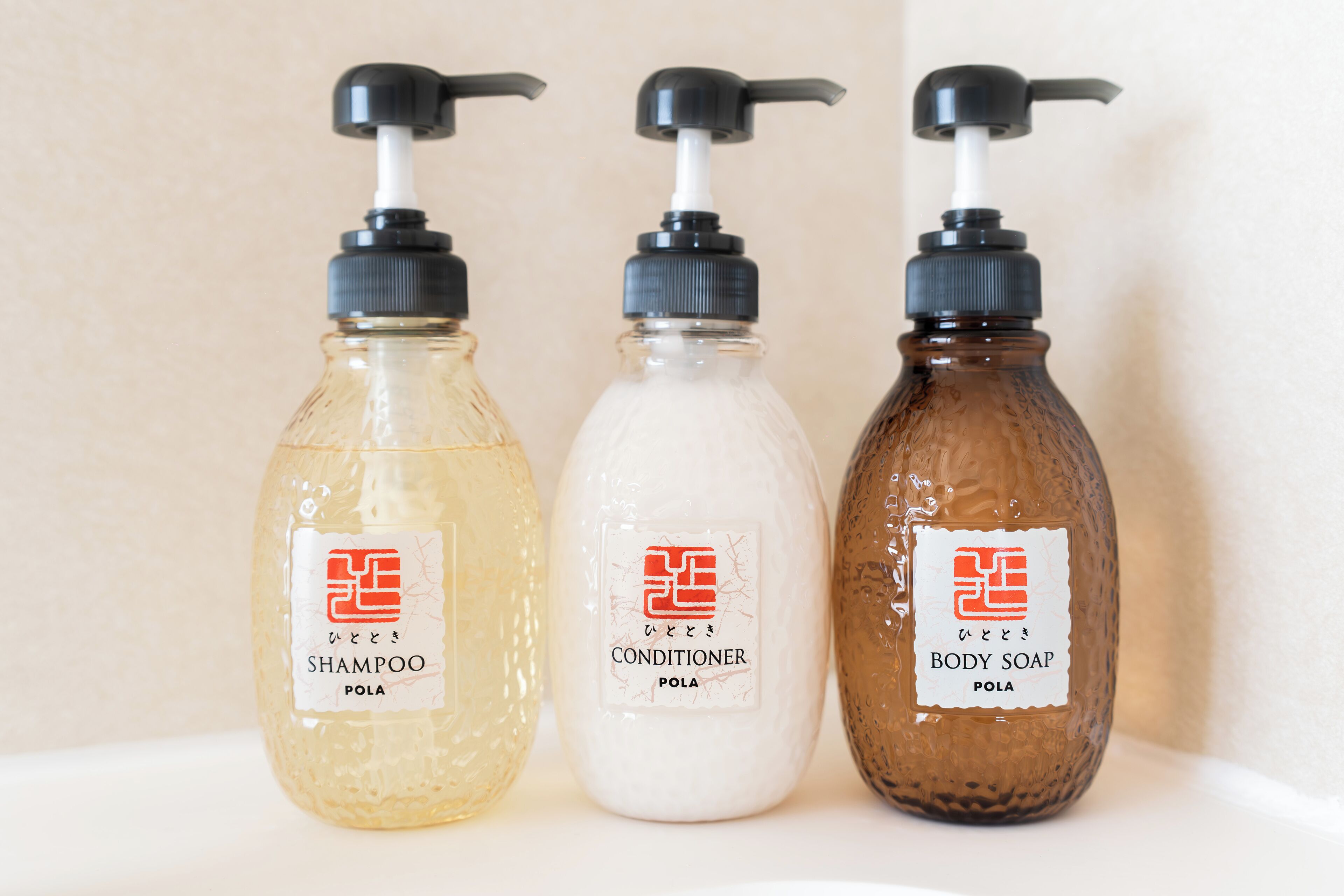 Three bottles of liquid soap with pump dispensers, labeled as shampoo, conditioner, and body soap.