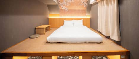 Una habitación de hotel moderna con una cama grande, una mesita de noche de madera, una pequeña mesa y un panel decorativo en la pared.