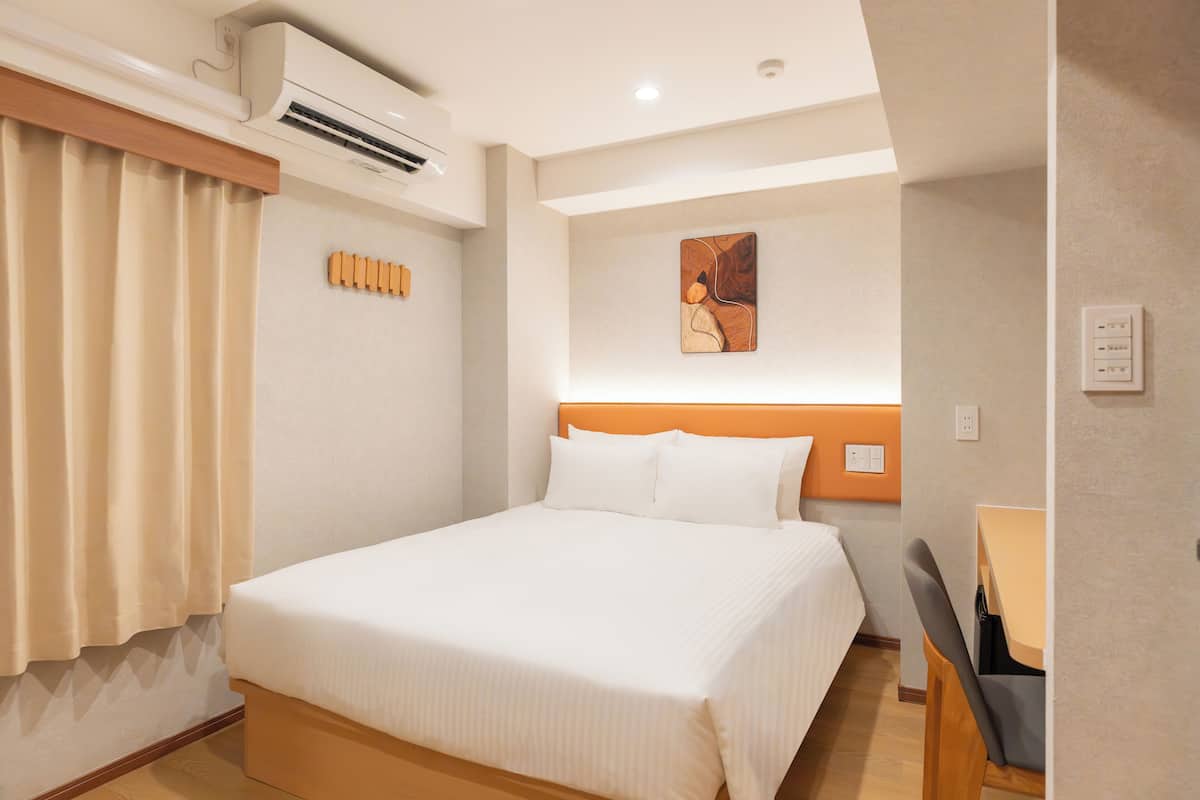 Una camera d'albergo con un letto, una scrivania e un condizionatore d'aria.