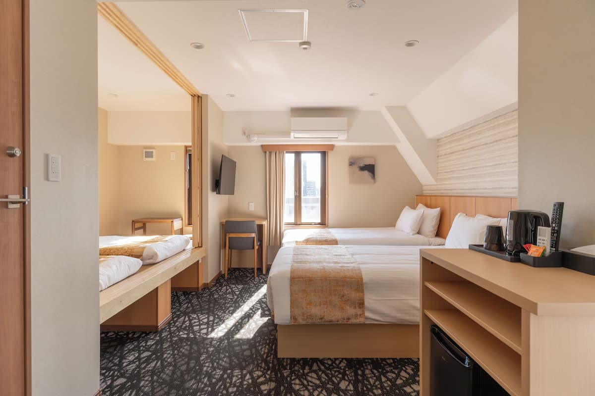 Una camera d'albergo con due letti, una scrivania, una sedia, una televisione e una macchina per il caffè.
