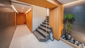 A modern interior with a staircase, wooden paneling, and a potted plant.