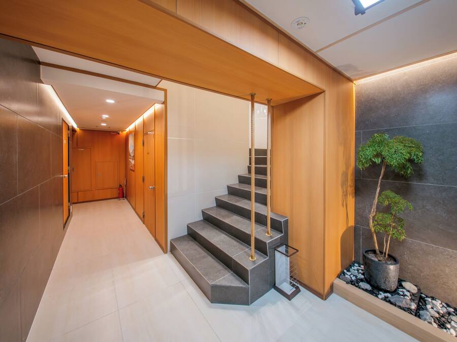 A modern interior with a staircase, wooden paneling, and a potted plant.