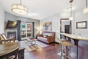 A modern living room with a fireplace, a sofa, a TV, and a dining area with a table and chairs.
