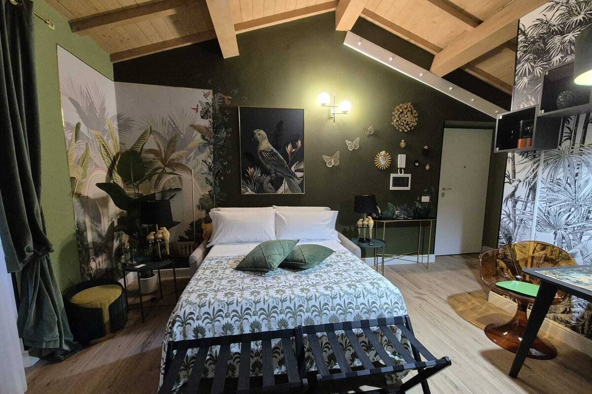 Une chambre à coucher avec un lit, un bureau et une chaise. Les murs sont décorés et le plafond est orné de poutres en bois.