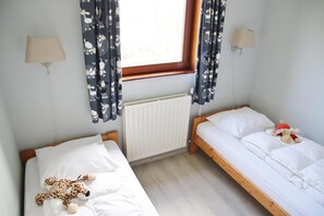 A room with two beds, a window with curtains, a radiator, and wall-mounted lamps. - Fantastic Holiday Home by the sea (Sint Maartensvlotbrug)