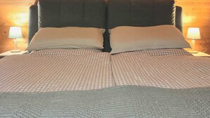 A bed with a checkered bedspread, two pillows, and a blanket. There are three framed pictures on the wall above the bed.
