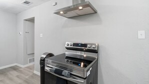 Una cucina moderna con forno in acciaio inossidabile e cappa aspirante, pareti bianche e pavimento in legno.