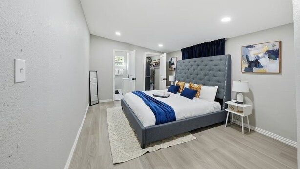 Una camera da letto moderna con un letto grande, una testiera grigia e un comodino con una lampada.