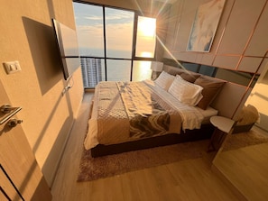 Een moderne slaapkamer met een groot bed, een televisie en uitzicht op de stad.