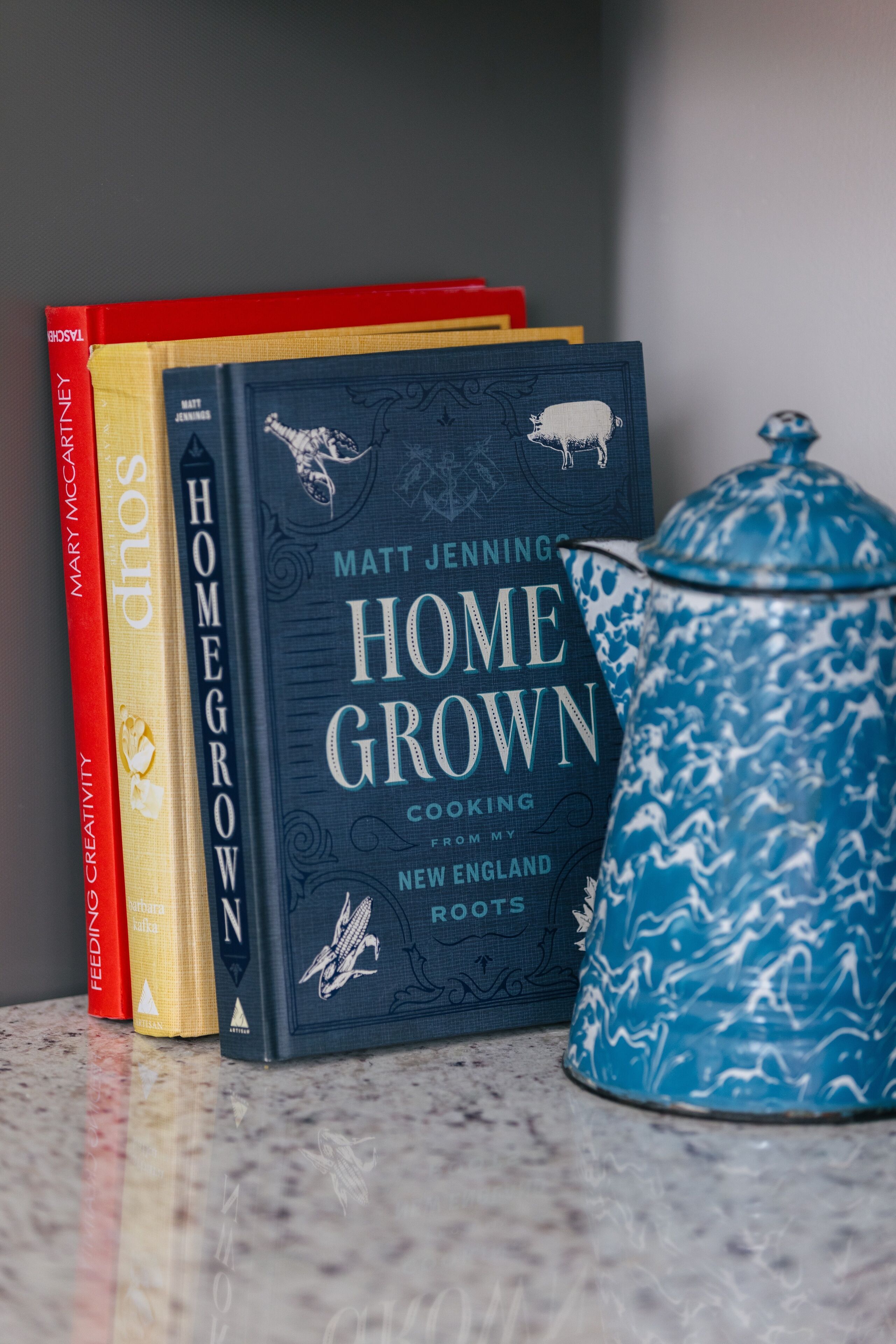 A stack of books with a blue patterned container.