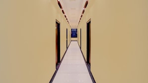 Un pasillo largo y estrecho con puertas a ambos lados, que conduce a una habitación oscura al final.
