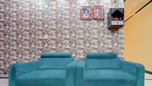 Una habitación con pared de piedra, dos sofás azules y un estante con objetos decorativos.