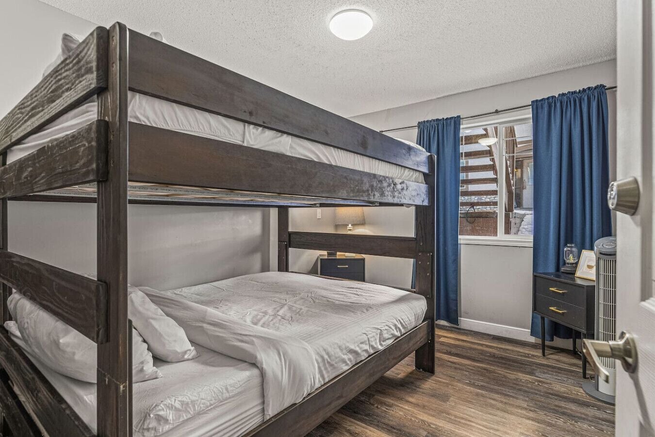 Habitación con literas, una mesita de noche y una puerta, con ventana.