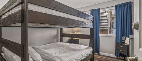 Habitación con literas, una mesita de noche y una puerta, con ventana.