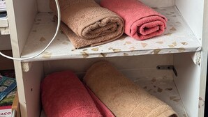 Ein Badezimmer mit gefliesten Wänden, einem Ablagefach mit Handtüchern und einer dekorativen Fliese.