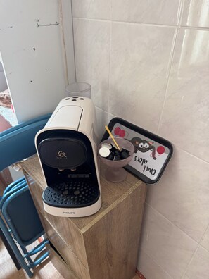 A coffee machine on a wooden counter with a tray of coffee cups and a cat-themed mug holder. - At DAGHSEN (Nice)