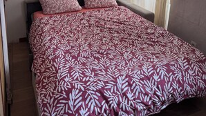Ein Schlafzimmer mit einem Bett, zwei Kissen, einem Bild an der Wand und einem Fenster mit Vorhängen.