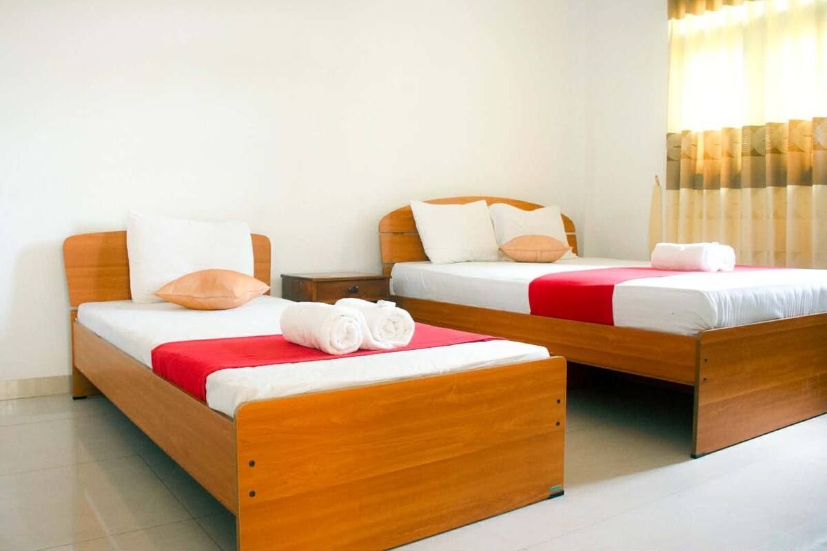 Ein Hotelzimmer mit zwei hölzernen Betten, jeweils mit weißer Bettwäsche und roten Decken.