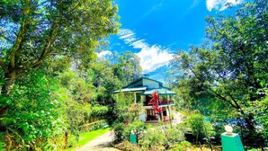A house surrounded by lush greenery, with a clear sky and a pathway leading to the entrance. - Blue Mountain Resort Bandarawela  (Bandarawela)