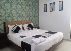 A neatly made bed with a white and black bedspread, a wooden headboard, and a patterned wallpaper in the background.