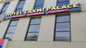 Μια πινακίδα ξενοδοχείου με την ένδειξη «HOTEL LAXMI PALACE» στον 2ο όροφο, η οποία υποδεικνύει ότι υπάρχει διαθέσιμο δωμάτιο με κλιματισμό.