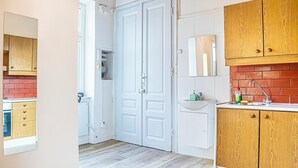 Eine Küche mit weißen Schränken, einer roten Ziegelrückwand und einer Holzausziehtafel.