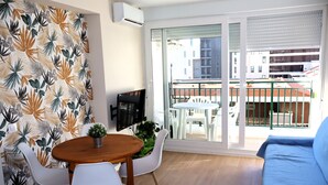 Un balcon avec une table et des chaises, un canapé et un téléviseur.