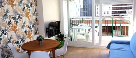 A balcony with a table and chairs, a sofa, and a TV.