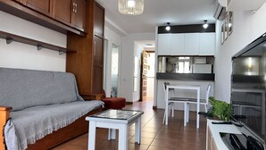 Un salon comprenant un canapé, une petite table et un coin cuisine avec une table à manger et des chaises.