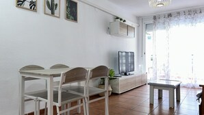 Un coin repas avec une table et des chaises, un téléviseur et un meuble agrémenté de plantes.