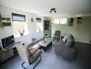 A living room with a television, seating, a coffee table, and a bookshelf. - Charming Beachside Base in Noordwijk (Noordwijk)