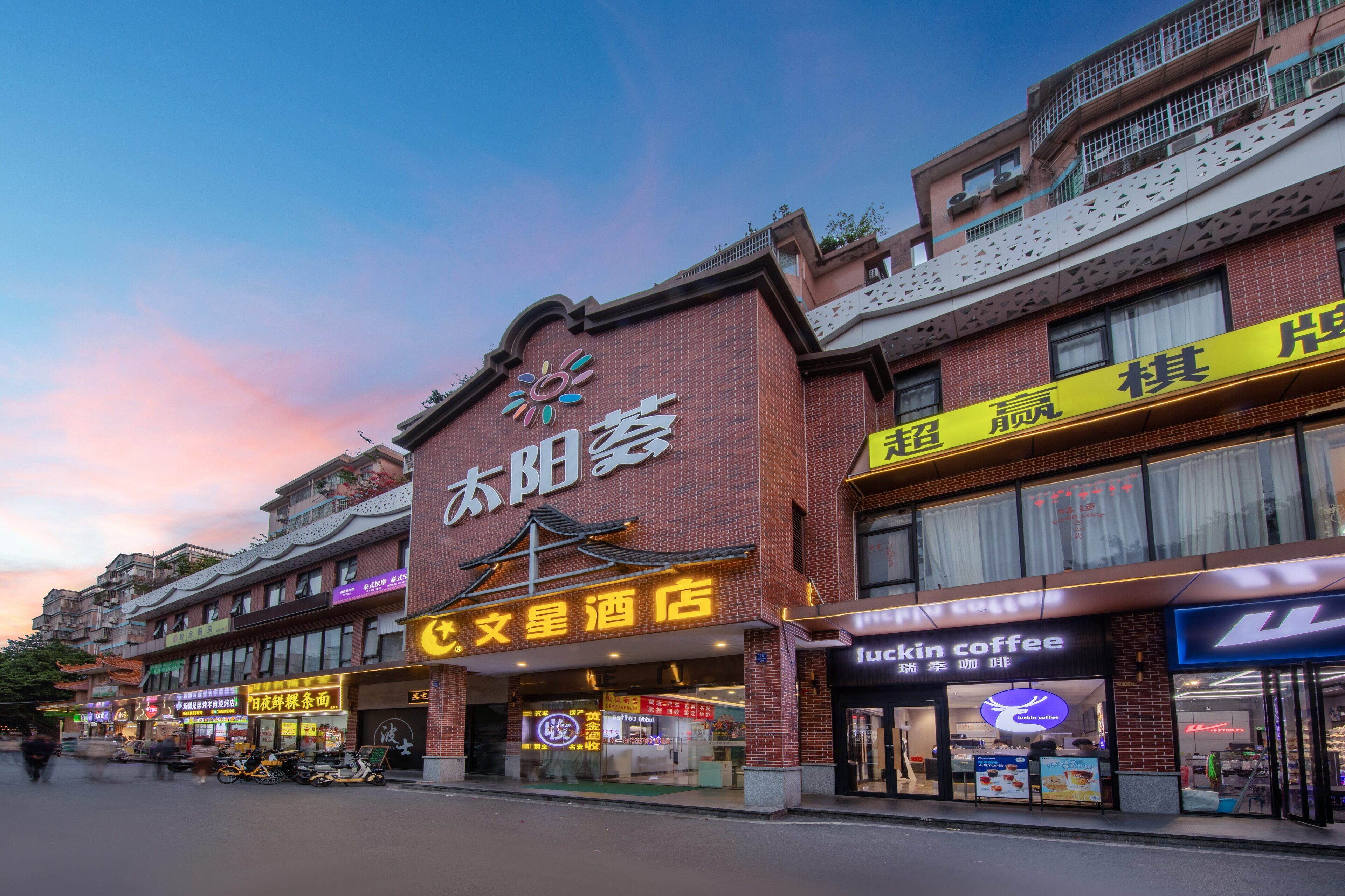 A hotel with a traditional architectural style, featuring a prominent sign with Chinese characters and a modern coffee shop adjacent to it.