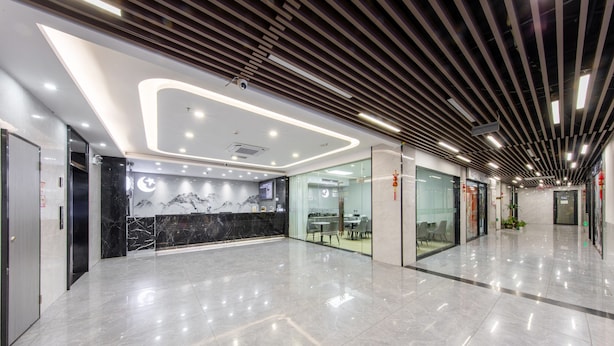 A modern lobby with a marble reception desk, glass walls, and a polished floor.