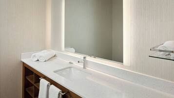 Un baño moderno con un espejo grande, un lavabo blanco y un perchero para toallas.