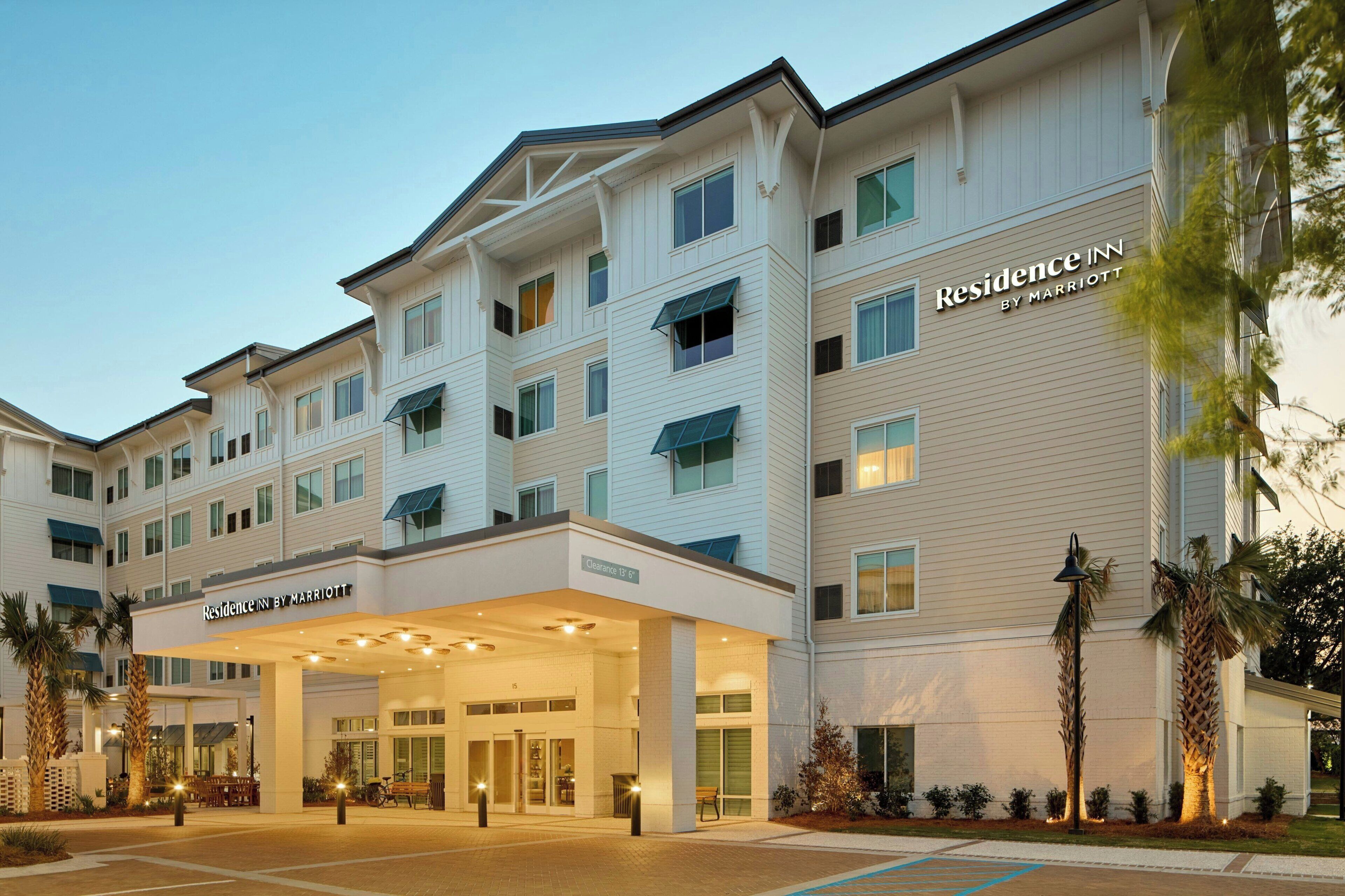 Monikerroksinen hotelli, jossa on näyttävä sisäänkäynti, kyltti, jossa lukee ”Residence Inn by Marriott”, ja pysäköintialue sen edessä.