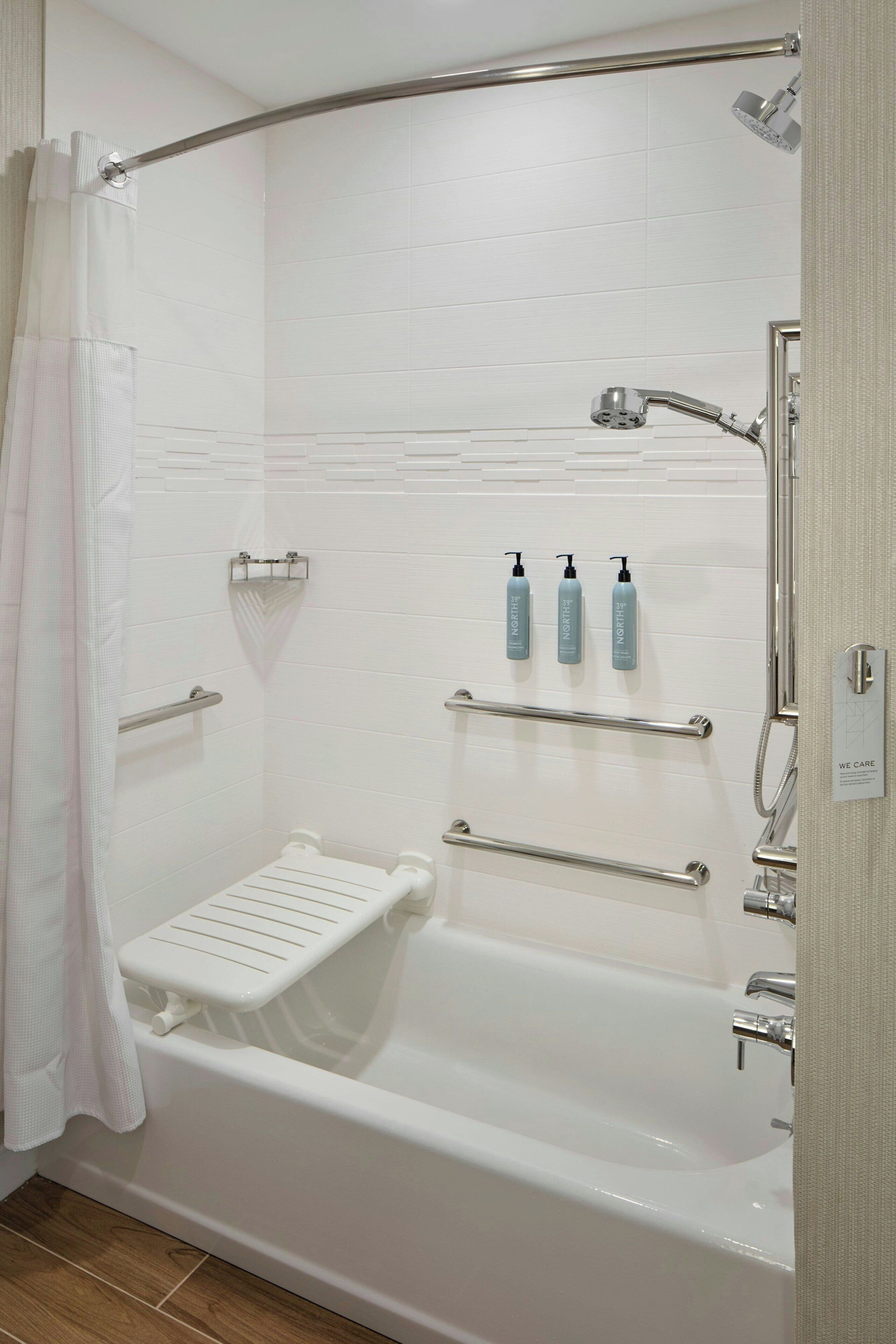 Een moderne badkamer met een inloopdouche, handgrepen, een witte badkuip en een handdoekrek.