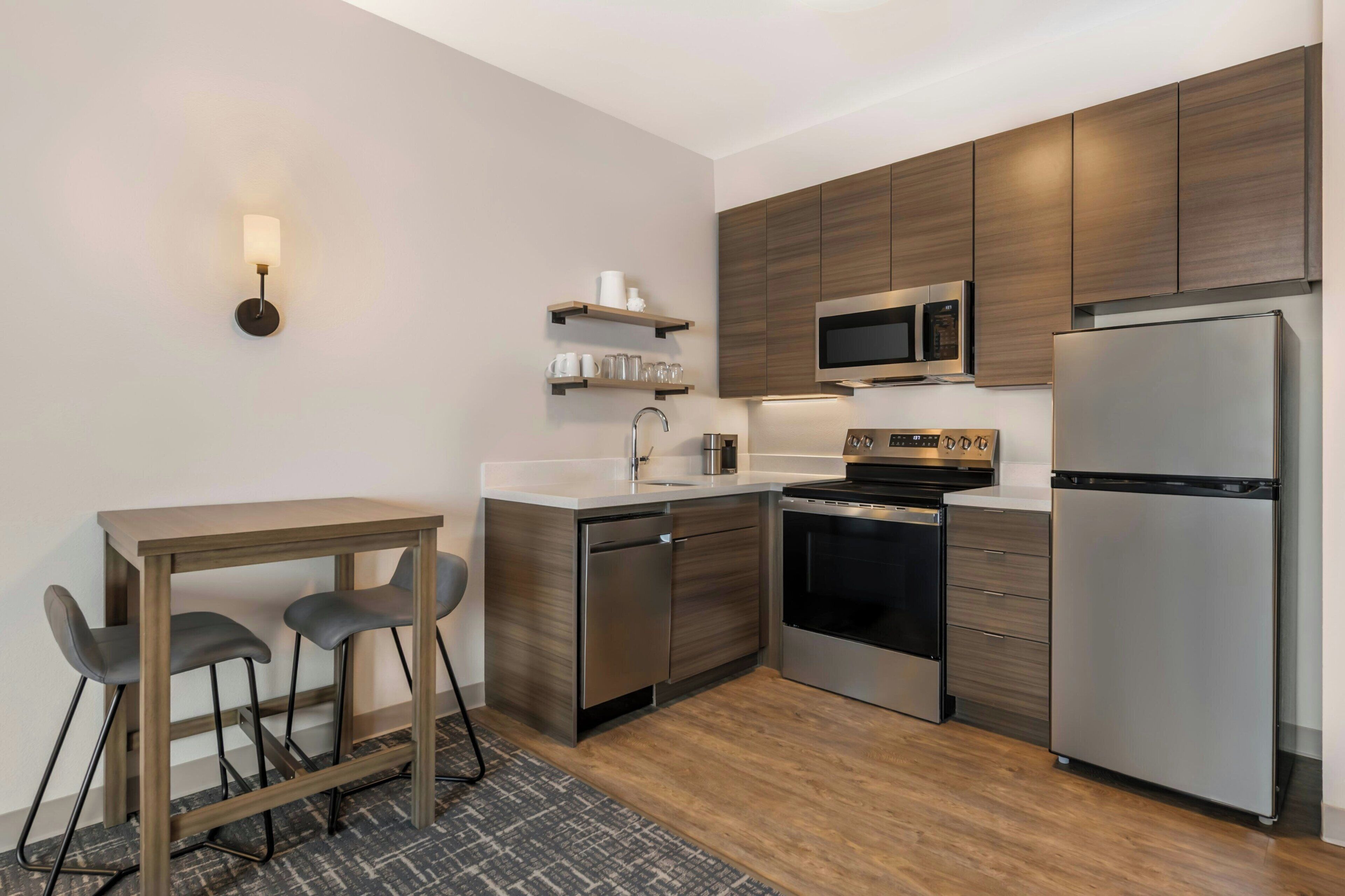 A modern kitchen with stainless steel appliances, wooden cabinets, and a bar area.