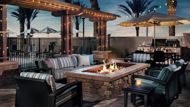 An outdoor patio with a fire pit, seating, umbrellas, and a grill area. - Residence Inn By Marriott Glen Allen Richmond (Glen Allen)