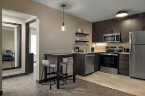 A modern kitchen with a built-in microwave, oven, and refrigerator. There is a bar area with stools and a pendant light. - Residence Inn By Marriott Glen Allen Richmond (Glen Allen)