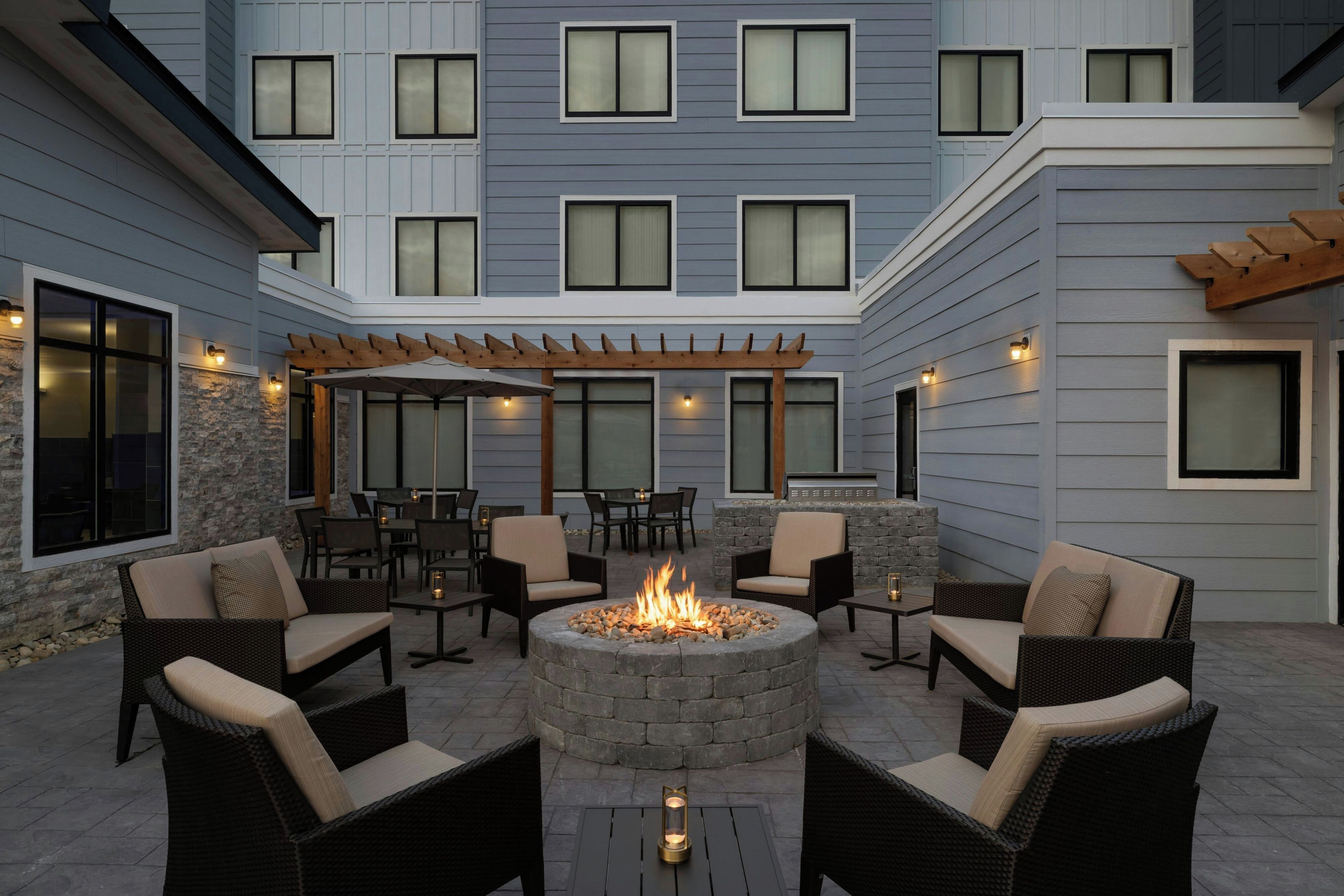 A courtyard with a fire pit, outdoor seating, and a pergola.