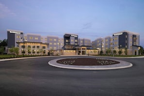 A multi-story hotel with a central entrance, a landscaped driveway, and a clear sky. - Residence Inn By Marriott Glen Allen Richmond (Glen Allen)