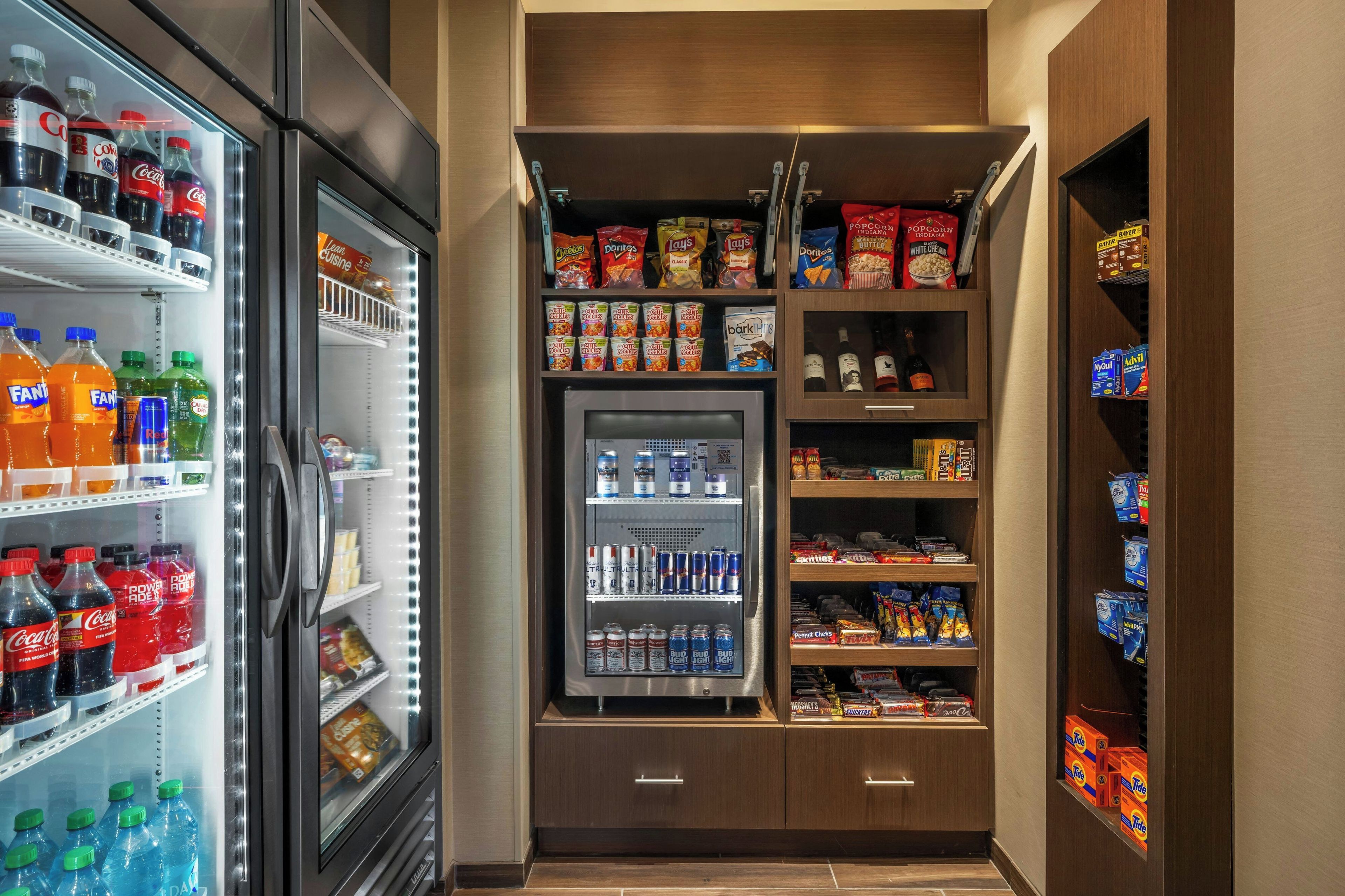 Un elegante minibar fornito di snack, bevande e un frigorifero pieno di bibite.