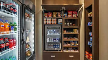 Un elegante minibar fornito di snack, bevande e un frigorifero pieno di bibite.