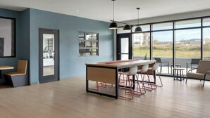 Una cocina moderna con una isla central, taburetes de bar y grandes ventanales que dan al exterior.
