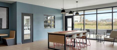 A modern kitchen with a central island, bar stools, and large windows offering a view of the outdoors.
