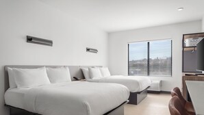 Una habitación de hotel moderna con dos camas, un escritorio y una ventana con persianas.